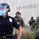 A police officer stands with armed members of the National Guard facing protesters marching over the death of George Floyd on June 1, 2020 in Los Angeles, California.